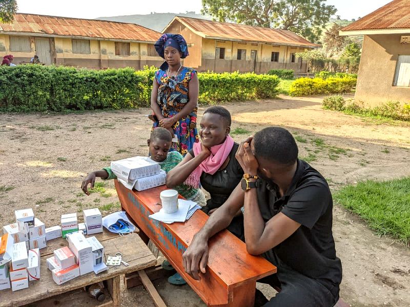People gather at an outreach desk covered with medicines in the late afternoon